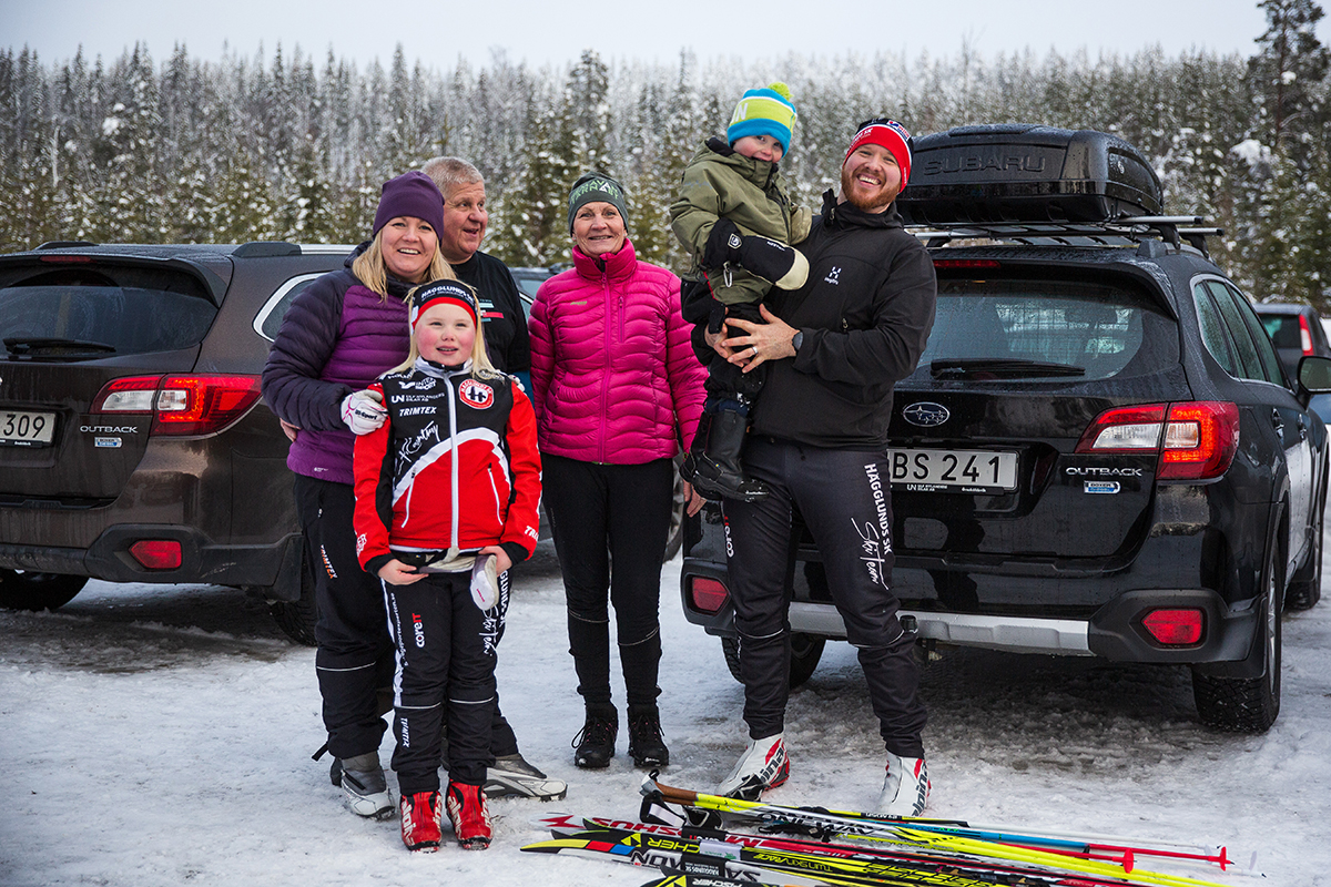 Familjen står framför bilarna